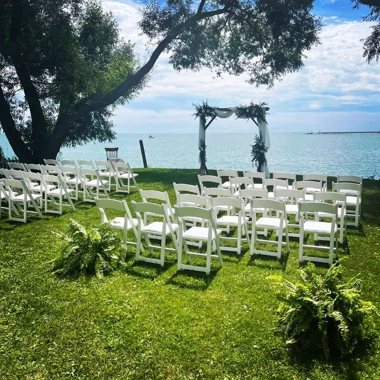 Outdoor wedding with white chairs overlooking the water